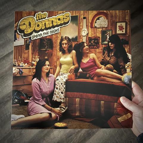 Album cover for Spend The Night by The Donna’s, featuring a photograph of four women in a messy room, looking assured and confident.