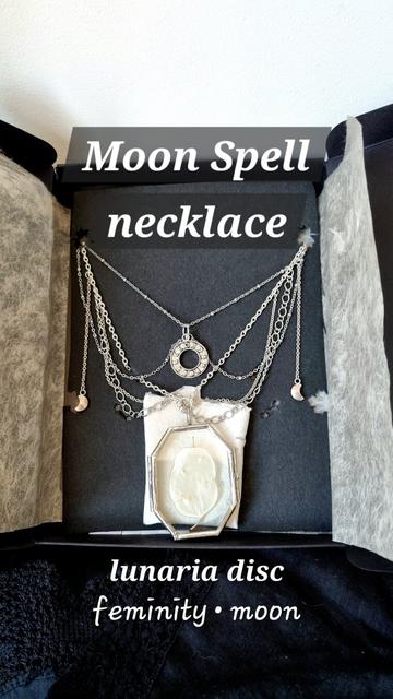 The necklace to be won seen closer with its name written (“Moon Spell”), what it contains (a “lunaria disc”, the latin name of the Honesty) and its symbolism (“femininity, moon”). We can better see the small crescent moons that fall on the sides of the necklace, the moon phase charm that falls in the hollow of the neck, the detail of the different chains and the glass pendant with its unique lunaria disc.
❉
Le collier à gagner vu de plus près avec écrit le nom du collier “Moon Spell”, ce qu’il contient (un “disque de lunaire”, l’autre nom de la Monnaie du Pape) et sa symbolique (“féminité, lune”). On voit mieux les petits croissants de lune qui tombent sur les côtés du collier, la breloque des phases de la lune qui tombe dans le creux du cou, le détail des différentes chaînes et le pendentif en verre avec son disque de lunaire unique.