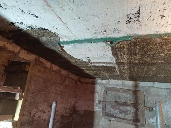 The ceiling is made from steel beams with concrete between them. For unknown reasons the bottom was covered in tar paper, which has been partially torn or crumbled off. It looks like the concrete was cast directly onto the tar paper, so perhaps it was part of the mold. The steel beams are still painted green and have some welded on hoops, likely for transport.