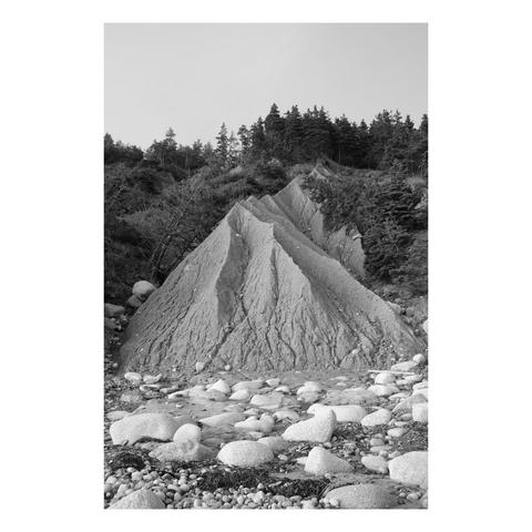 an eroding cliff composed of sand and small stones forming a large triangle at the edge of a rocky beach