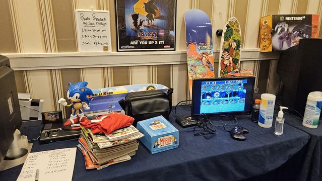 Donkey Kong skateboard decks, a Genesis Mini and a normal Genesis, Mario quiz cards, Sonic the Hedgehog 2 poster, and a Sonic figurine.
