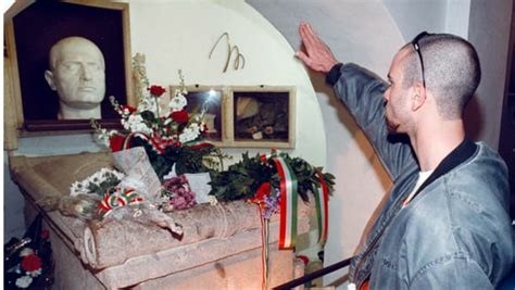 A cockroach in front of the tomb of the bigger cockroach (Mussolini's crypt in Predappio with a living fascist fuck doing the Roman salute)