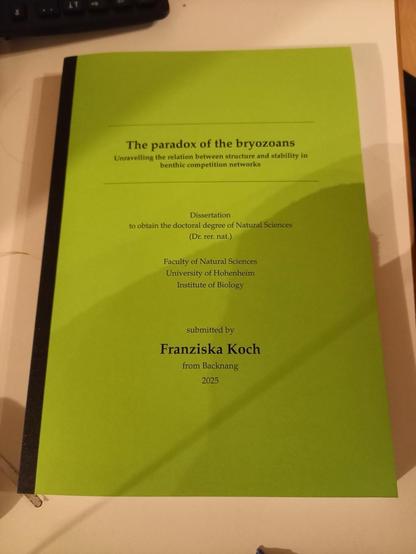 Printed copy of a PhD thesis. The title reads „The paradox of the bryozoans - unraveling the relation between structure and stability in benthic competition networks“ by Franziska Koch. The title page is bright green.