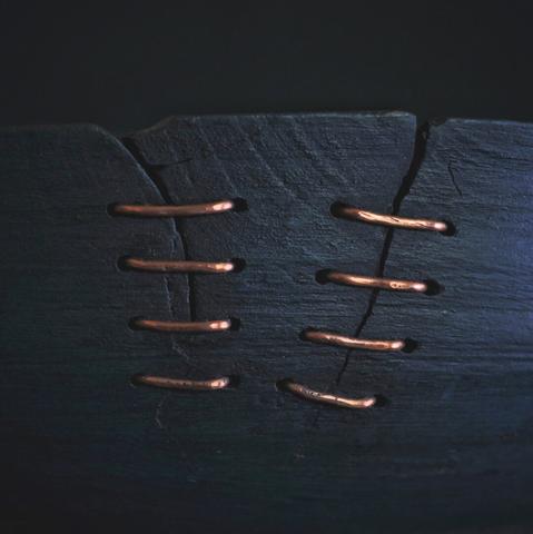 Closeup of a repaired bowl. The bowl has been repaired with a copper wire.