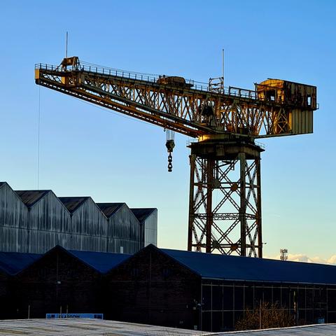 A large industrial crane looming over former shipyard buildings.