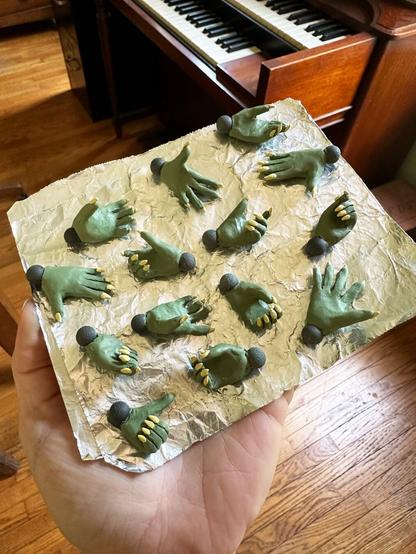 a set of green clay hands with yellow fingernails that are used to animate a claymation puppet