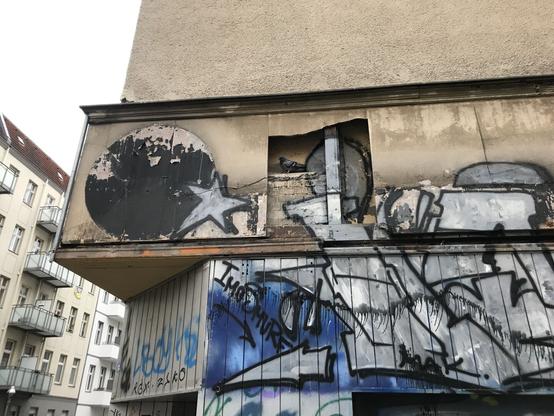 Detail einer kaputten Wand mit silbernen Buchstaben drauf gesprüht