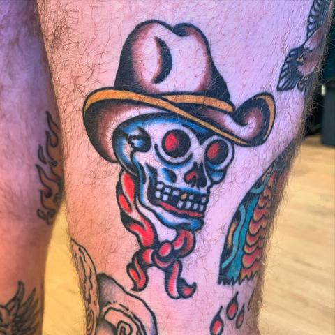 Healed tattoo of a skull with a cowboy hat in American traditional style