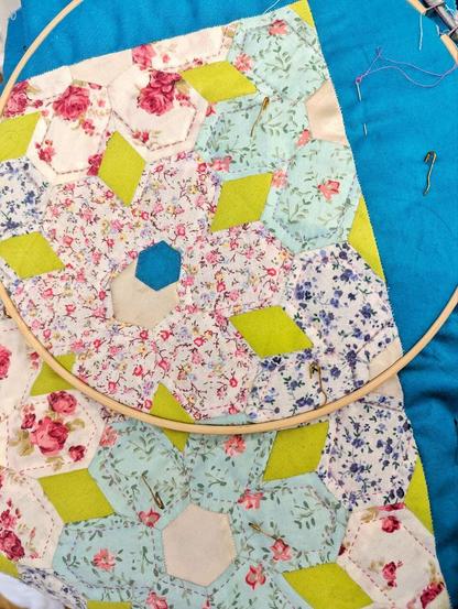 Big embroidery hoop with colourful flower EPP patchwork which is now being quilted.