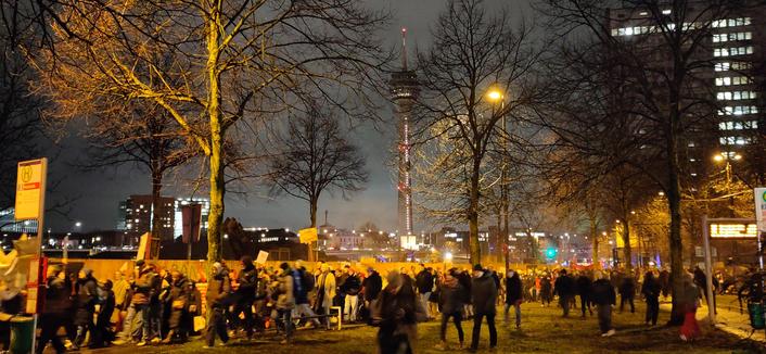 Abendlicher Demonstrationszug im Dunkeln mit Straßenbeleuchtung. Im Hintergrund der Düsseldorfer Fernsehturm.