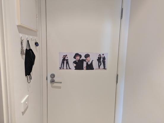 View of the same poster from a bit further back, showing how it is positioned on the back of a door, with hooks for keys and masks to one sode
