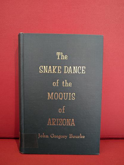 The book "The snake dance of the Moquis of Arizona" by John Gregory Bourke in front of a red background