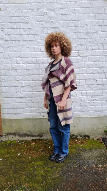 A person wearing a knitted kimonos with horizontal stripes to bypass cctv face recognition.