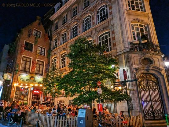 People sitting at outdoor tables sipping beer at night in a pub in the center of Brussels, Belgium