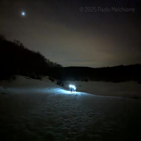 Group of night snowshoers on the Voltigno plateau, in the Gran Sasso mountain range, in Abruzzo.