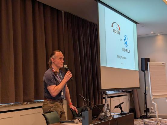 Gray haired man with ponytail giving a talk