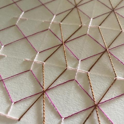 Close up image of a traditional woven sashiko style pattern stitched on paper.