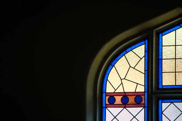 The frame is mostly negative space yet the lower right is a detail of an Arts & Crafts stain glass window with a peaked centre arch.