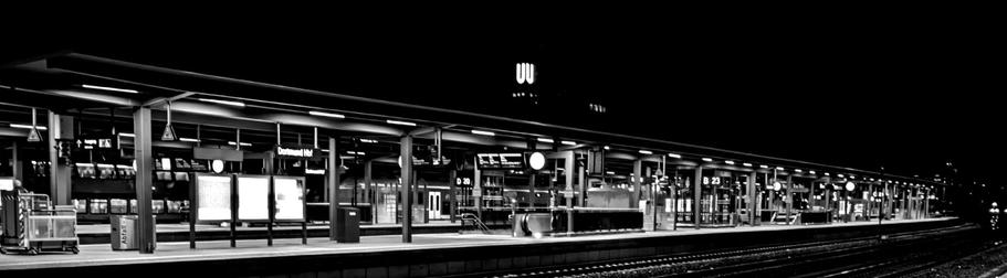 A black and white photo of a train station that captures the quiet atmosphere of the early morning. 

Ein Schwarz-Weiss-Foto eines Bahnhofs, das die ruhige Atmosphaere des fruehen Morgens einfaengt.