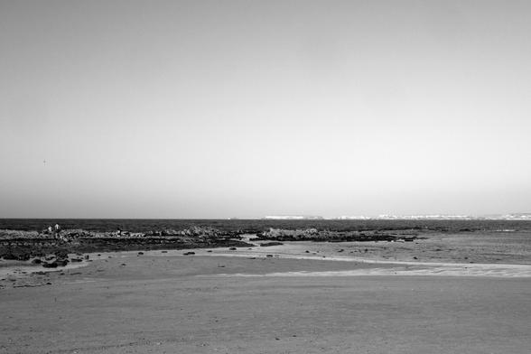 BW Photo of the seascape, taken at the beach on Peniche. The beach is mostly empty and in the background you can see the city.