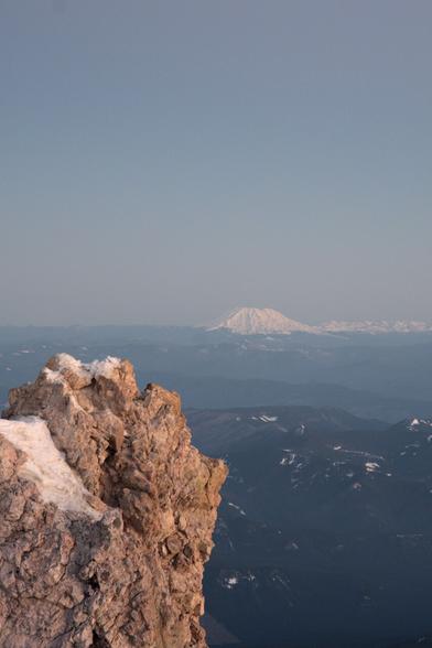 Mount saint helens distantly snow-covered with a foreground rock face.