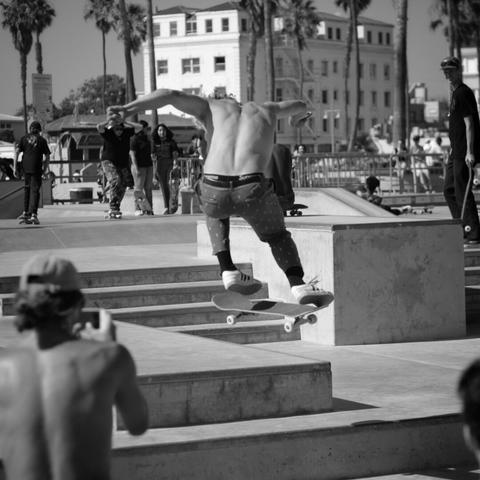 Black and white photograph of a skater doing a trick off some stairs