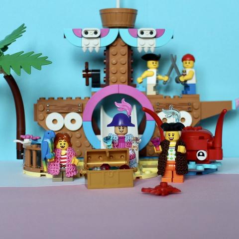 3 Lego pirate minifigs guarding a gold chest with treasure. In the background two kid pirates reenacting a sword fight.
