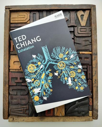 A photo of Ted Chiang's short story collection ‘Exhalation’. The cover art features an anatomical drawing of a pair of lungs overlaid with clockwork and little birds.