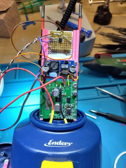 several PCBs mounted in a 3d printed, vertical frame. Standing on top of the camping lamp foot. (back view, looks more messy). brand name on the camping lamp is visible. name is 'enders'.