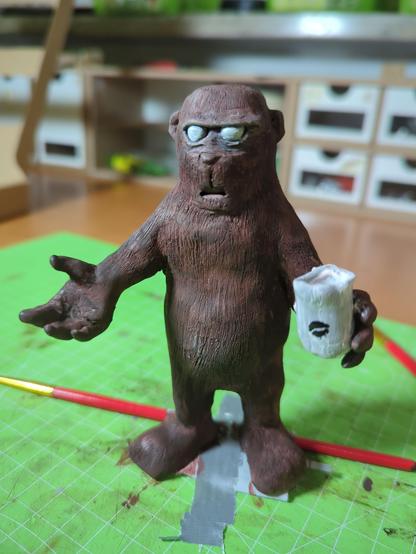 Verschiedene Ansichten einer Figur aus sculpey. Es ist ein Braunbär der auf den Hinterbeinen steht und die beiden Arme in einer sprachlosen Geste nach vorne streckt. In der linken Hand hält er einen Kaffeebecher auf dem eine stilisierte Kaffeebohne abgebildet ist.
