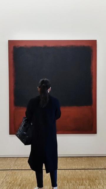 A woman in black facing Mark Rothko's artwork in Paris, Centre Pompidou (black and red rectangles on bloody red).