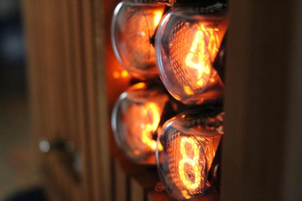 Close-up shot of the nixie clock from the right side, focusing on the stacked nixie tubes and the wood-clad façade surrounding it. The orange glow offers a nice contrast in addition with the distinct foreground versus the blurry background
