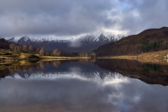 The foreground is Loch Coulin with a pretty good reflection of the mid and background scenery. The light casts brightly on brown grasses and heather leaving Beinn Eighe in the distance quite dark.