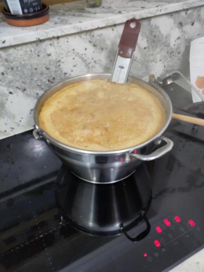 a large pan on a stove, boiling vigorously, with hubbling & bubbling and orange bubbles