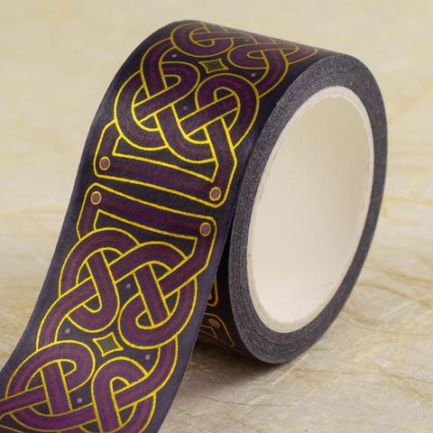 A roll of 25mm-wide washi tape with a traditional Celtic knot design in shades of purple with a green accent and metallic gold lines, partly unrolled to show the design.