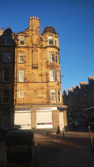 Golden winter light on the old stones of a Victorian tenement, with a long line of shadow from the opposite building