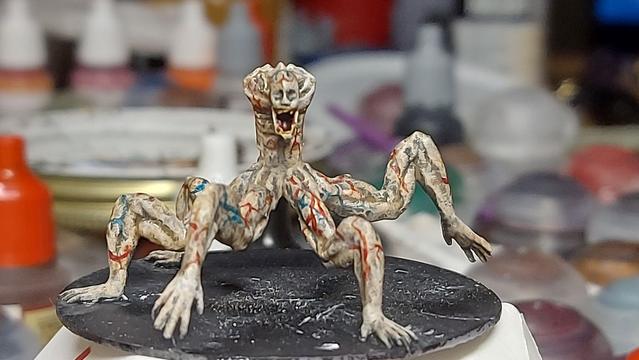 A painted 3D printed mini-figure of the previously-described monster. It has red and blue veins all over it.