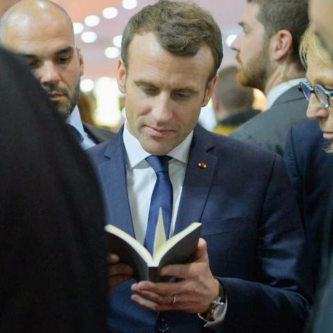 Emmanuel Macron lisant un livre au milieu de la foule
