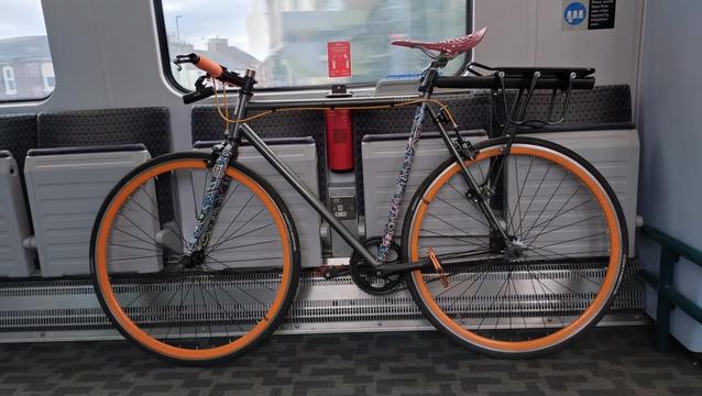 Single speed bike with orange wheels on a train