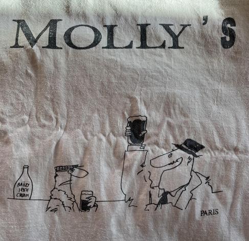 Photo of a white t-shirt with the logo “Molly’s”, and a man holding a pint of Guinness aloft.