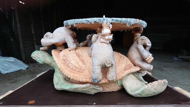 Discworld.
Green turtle standing on brown box. Four elephants on top of Turtles light brown shield, holding disc up. One turtle seems to be giving driving lessons to turtle, on is drinking coffee. One stares to emptynes. There's also books between turtle, elephants and Discworld.