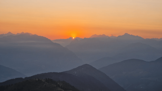 A sunrise in Italy, in the mountains, with the sun that is appearing between two mountains. Red sky.