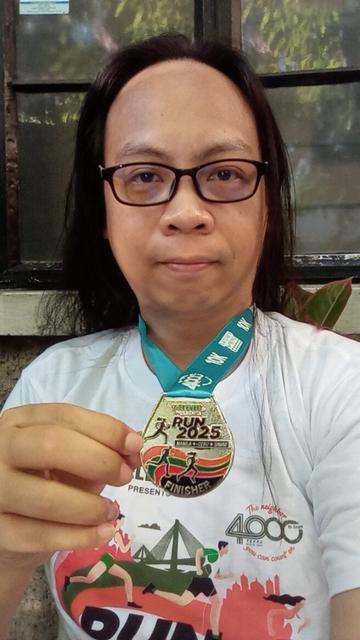 Me holding the 10m finisher medal while wearing the 10k finisher t-shirt