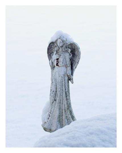 Stone angel statue dusted in snow.