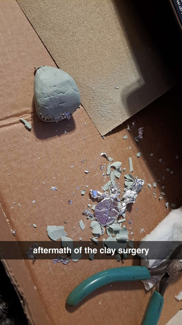 A photo of clay destruction, there is aluminum foil and clay debri all over and a sad lump of clay with the bottom torn out. 
Text on the photo reads "Aftermath of the clay surgery"