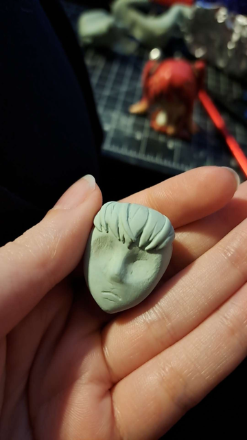 A photo of a work in progress head sculpt of the character Adelie from the anime Space Dandy. Her face is very roughly sculpted while her bangs are mostly done. Her expression is neutral.