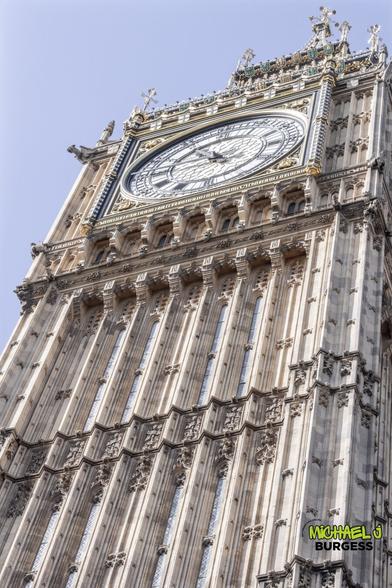 A dramatic close-up of Big Ben showcases the intricate Gothic Revival details of its façade. The clock face gleams under soft daylight, emphasizing this iconic London landmark's ornate craftsmanship and historical grandeur.
