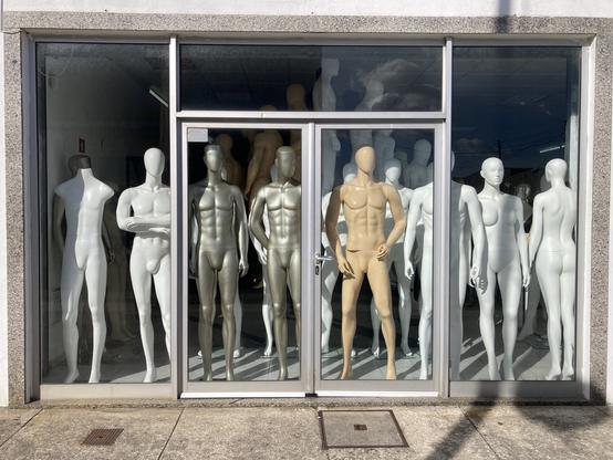 Numerous unclothed mannequins in the window of a shop which sells only mannequins