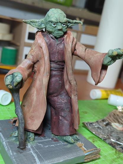 Verschiedene Ansichten einer selbstgemachten Figur von Meister Yoda. Die Figur ist aus sculpey und angemalt. 
Yoda steht da, eine Hand nach vorne gestreckt, die andere auf seinem Stock abgestürzt