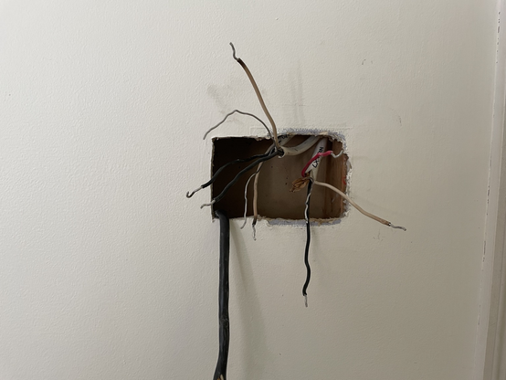 Romex wires coming out of a hole in a sheet rock wall